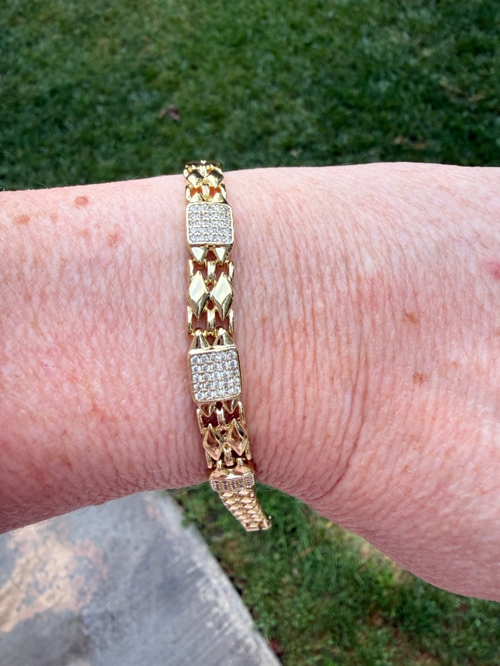 Gold bracelet with a watchband style band and 3 square pave accent boxes.